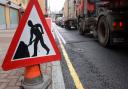 A men at work road sign next to a traffic jam in central London