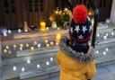 A child adds a candle to the tribute on the steps of the Barking town hall.