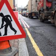 A men at work road sign next to a traffic jam in central London