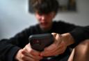 A teenager uses his mobile phone to access social media, (Dean Lewins/AAP via AP)