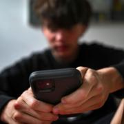 A teenager uses his mobile phone to access social media, (Dean Lewins/AAP via AP)