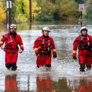 Firefighters walk through floodwaters while responding to a rescue call in Sonoma County, California (AP Photo/Noah Berger)